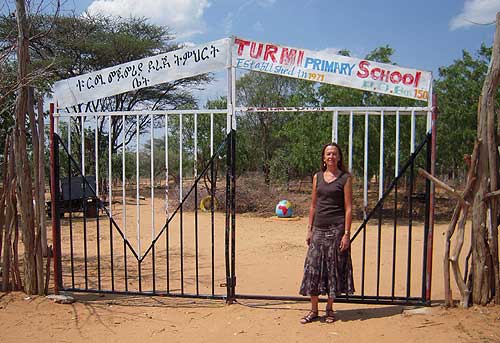 Woman in front of gate to new school in Ethiopia