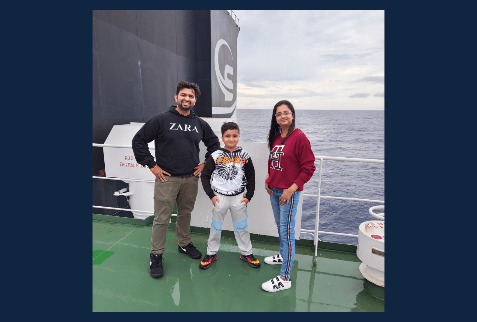 A family of three posing onboard a vessel.