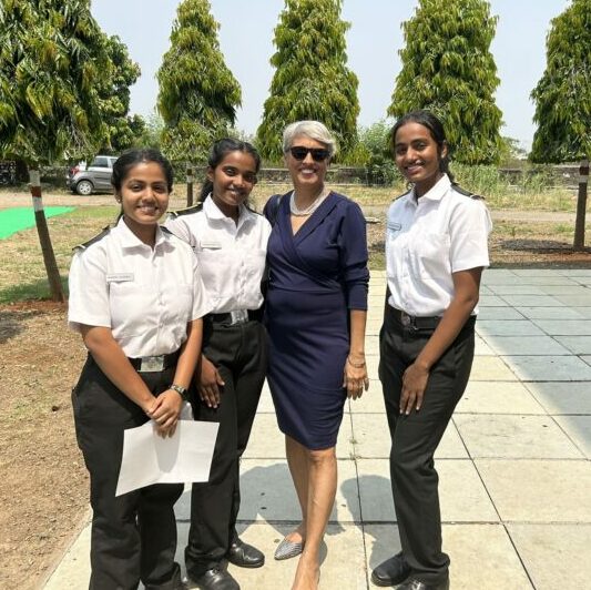 Girl cadets in uniform standing with their mentor.