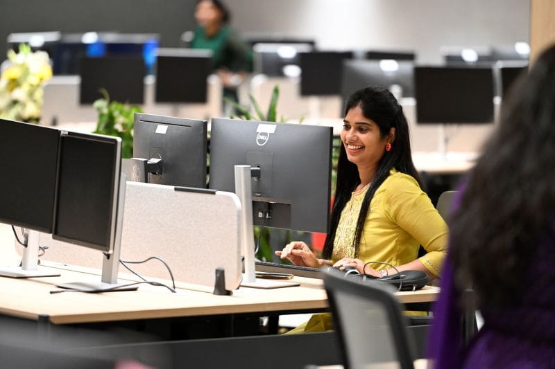 Women in yellow top seated at her desk.