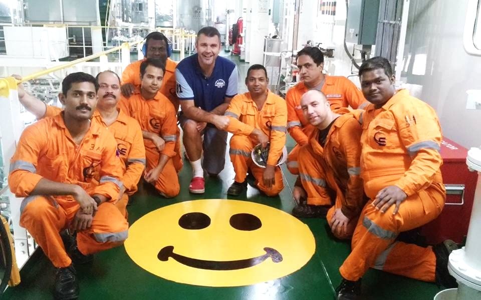 Engineering crew kneeling around a smiley face painted on the floor