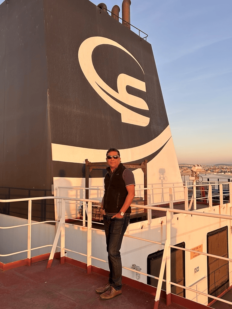 Yatin while onboard, posing on the bridge with the Scorpio logo on the fennel behind.